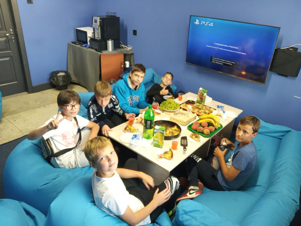 Діти їдять їжу у клубі віртуальної реальності. В цій кімнаті є Playstation та настільні ігри. Харків віртуальна реальність 2023 жовтень.